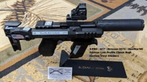 Custom-modified firearm with optic and stickers displayed on a stand.